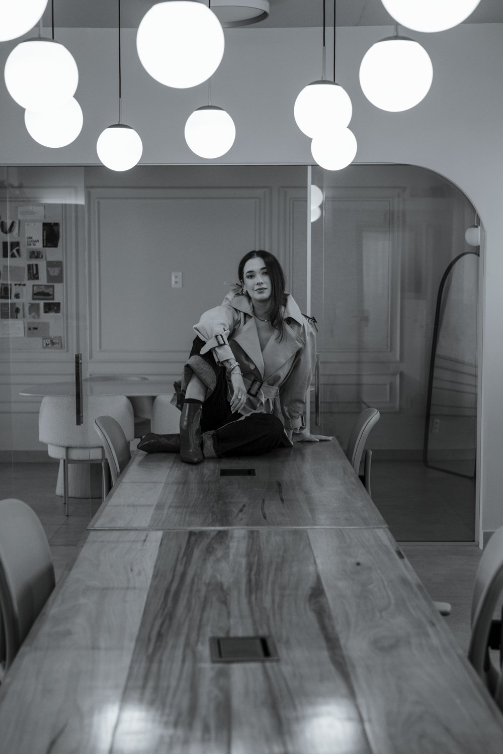 Bruna Mendes sentada sobre uma mesa de reunião